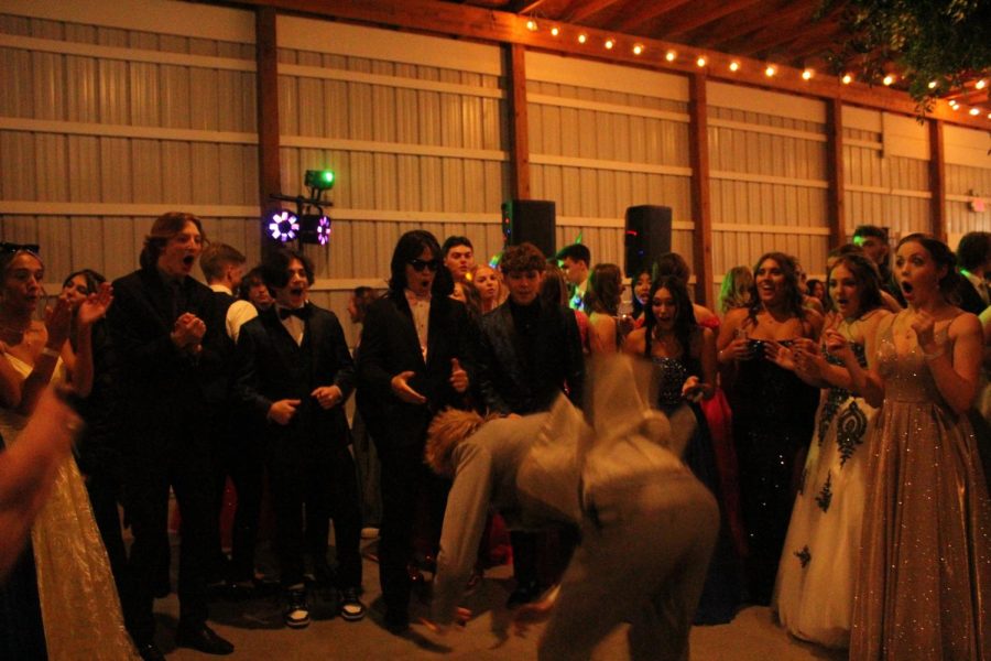 A prom guest does a backflip in the middle of the dance circle. The crowd was in awe after watching this guest do a backflip.