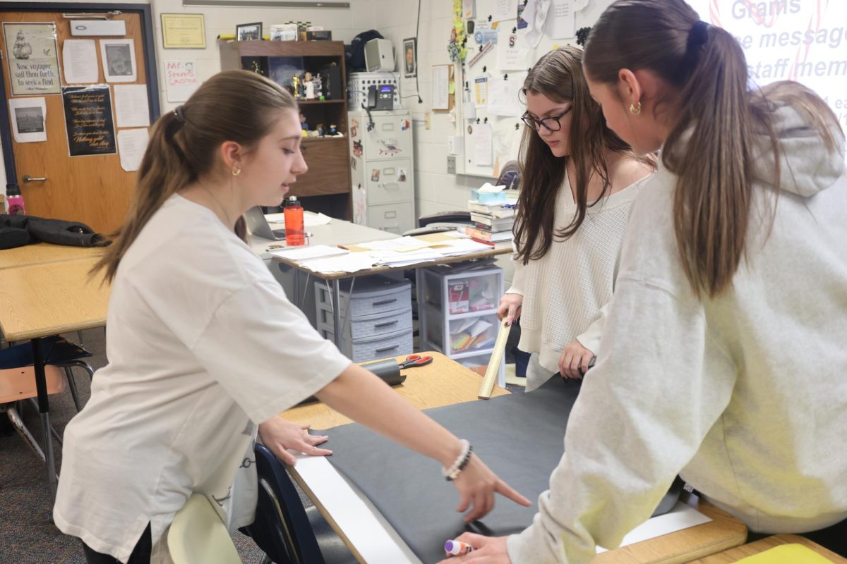 Students Addison Sklapsky, Kailynn Stricker-Batson, and Mariesa Stover (left to right) creating the design for their door. The group successfully completed this by bringing their ideas together.