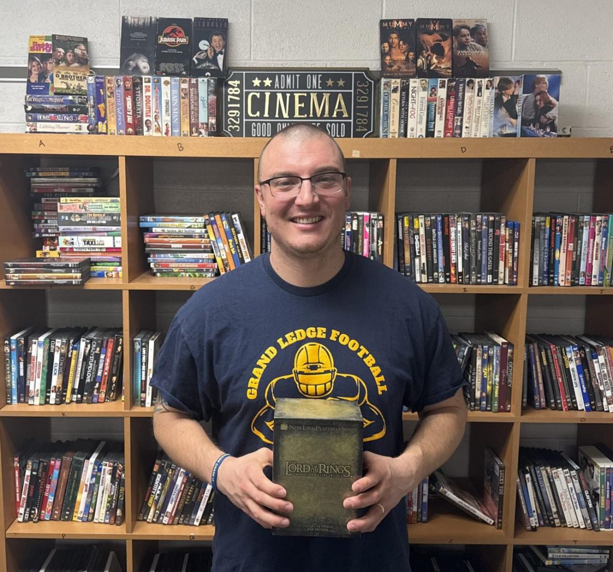 Vincent Cook gleefully holds up his beloved DVD set of his The Lord of the Rings trilogy. He pulled it from the notorious DVD shelf in his classroom.